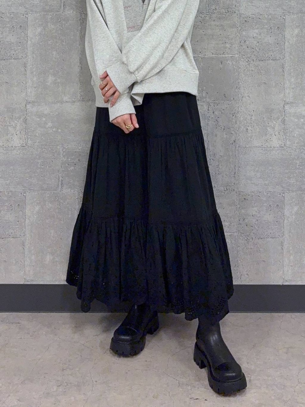 ブラック系のブーツ、ホワイト系のスウェット、ブラック系のスカートを着用したレディースの秋コーディネートの3枚目の写真