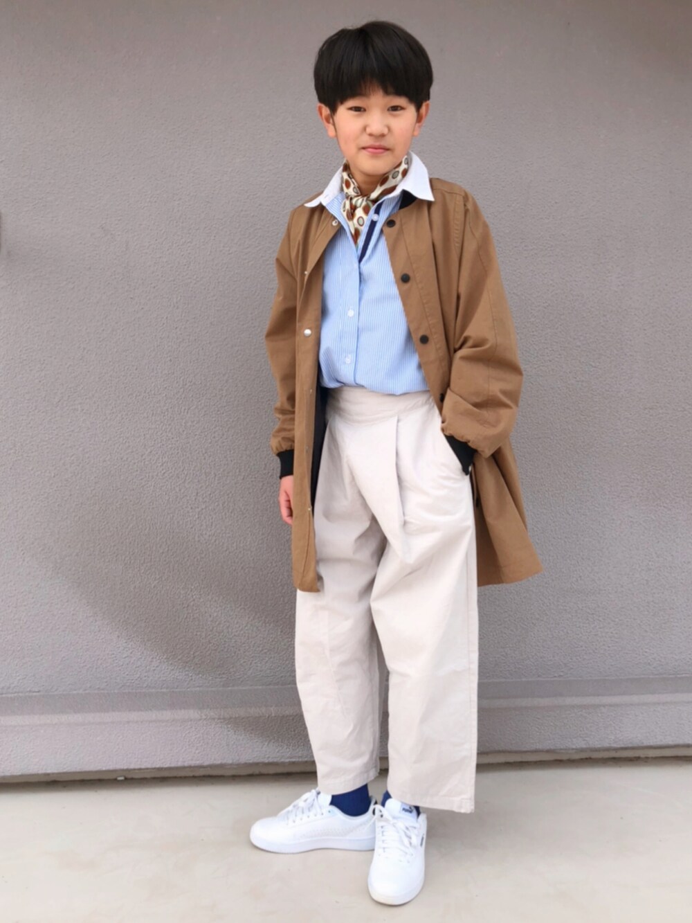 ホワイト系のスラックス、ホワイト系のスニーカー、ベージュ系のノーカラーコートを着用したキッズの春コーディネートの3枚目の写真