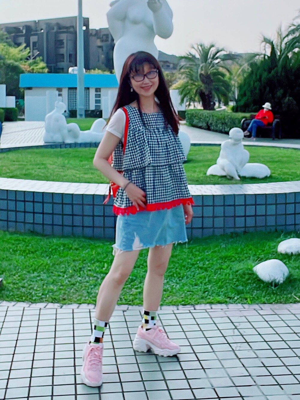 ブラック系のタンクトップ、ピンク系のスニーカー、ブルー系のデニムスカートを着用したレディースの春コーディネートの3枚目の写真