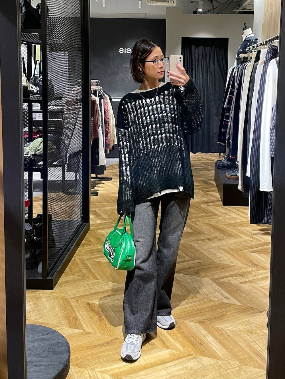 ブラック系のデニムパンツ、グリーン系のショルダーバッグ、ホワイト系のTシャツ/カットソーを着用したレディースの秋コーディネートの4枚目の写真