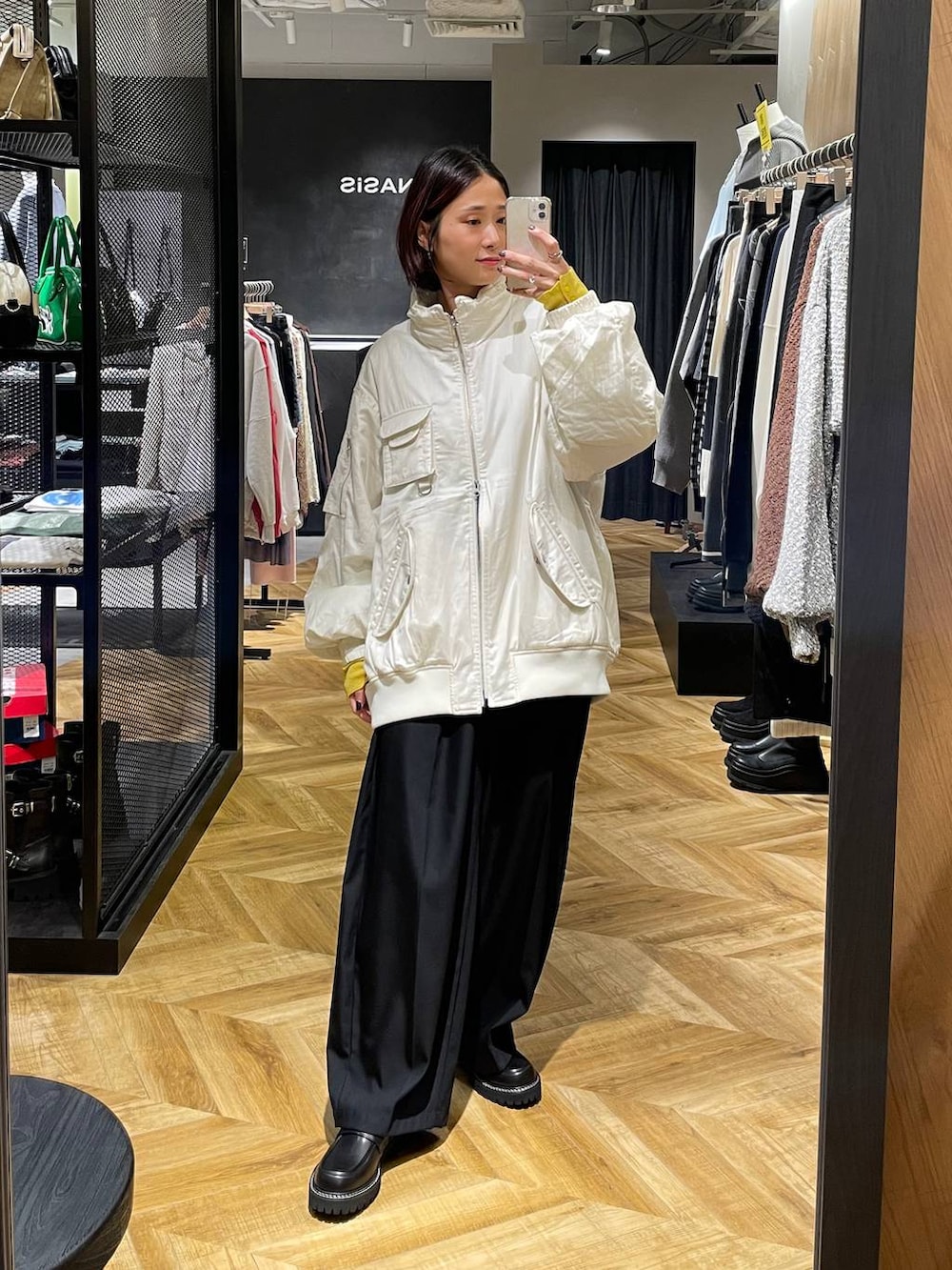 ホワイト系のブルゾン、ブラック系のローファー、ブラック系のスラックスを着用したレディースの秋コーディネートの2枚目の写真