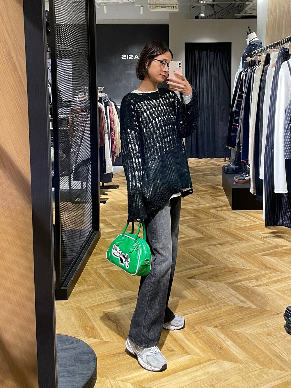 ブラック系のデニムパンツ、グリーン系のショルダーバッグ、ホワイト系のTシャツ/カットソーを着用したレディースの秋コーディネートの3枚目の写真