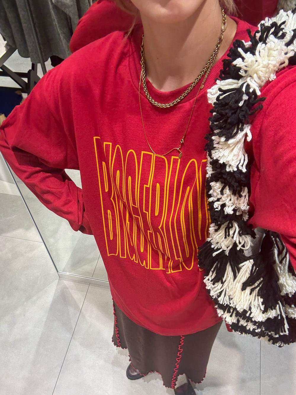 レッド系のTシャツ/カットソー、ブラウン系のスカート、ブラック系のローファーを着用したレディースの秋コーディネートの2枚目の写真