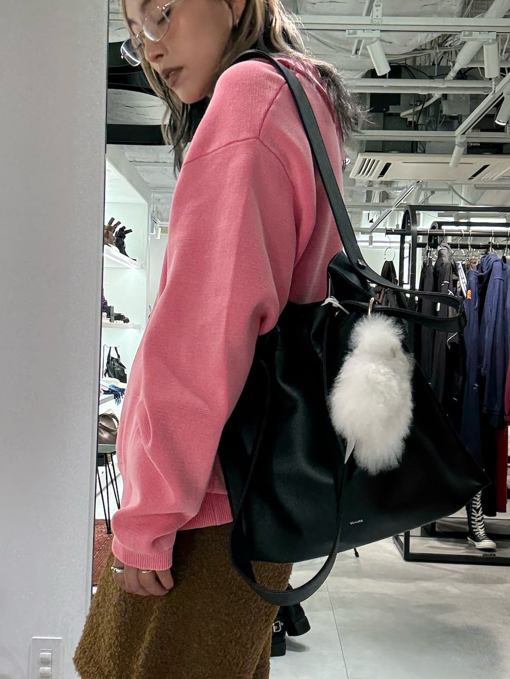 ピンク系のニット/セーター、ブラウン系のその他パンツ、ブラック系のトートバッグを着用したレディースの秋コーディネートの5枚目の写真