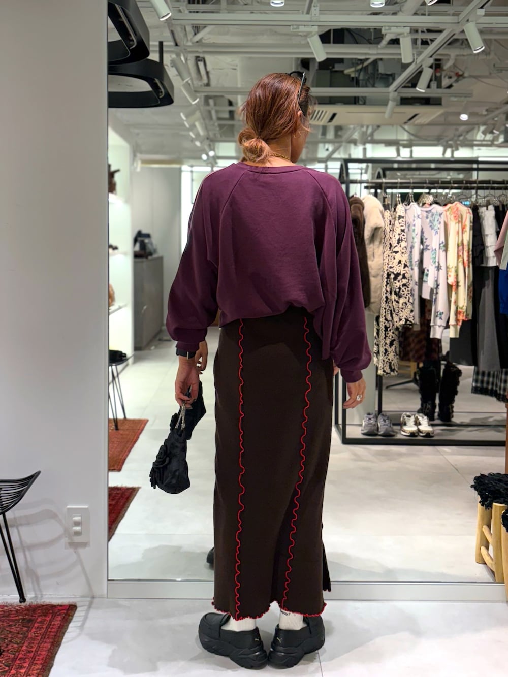 レッド系のスウェット、ブラウン系のスカート、ブラック系のトートバッグを着用したレディースの秋コーディネートの3枚目の写真