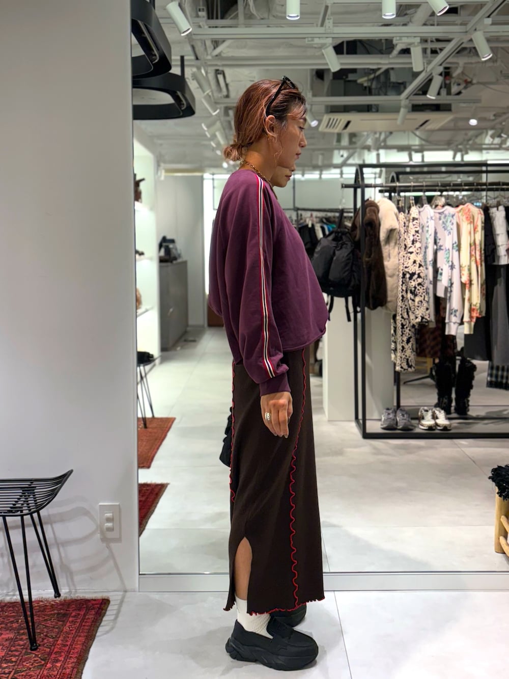 レッド系のスウェット、ブラウン系のスカート、ブラック系のトートバッグを着用したレディースの秋コーディネートの2枚目の写真