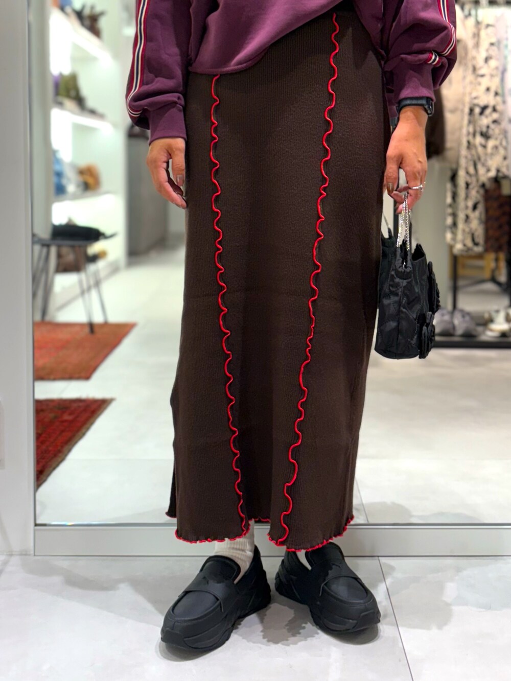 レッド系のスウェット、ブラウン系のスカート、ブラック系のトートバッグを着用したレディースの秋コーディネートの5枚目の写真