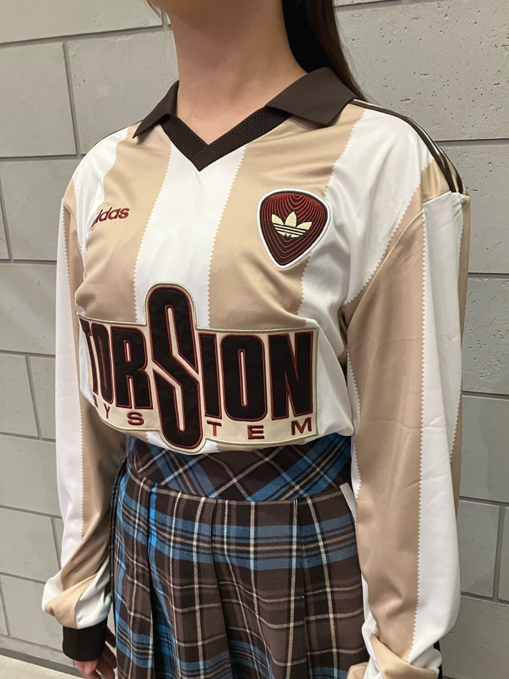 ブラウン系のスカート、ホワイト系のTシャツ/カットソー、ホワイト系のスニーカーを着用したレディースの冬コーディネートの2枚目の写真