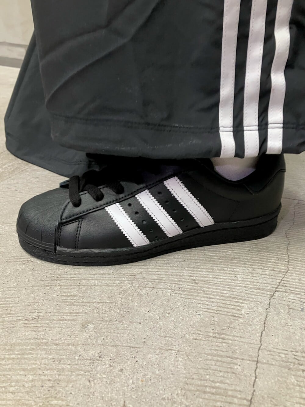 ホワイト系のジャージ、ブラック系のスウェットパンツ、ブラック系のシューズを着用したレディースの冬コーディネートの4枚目の写真