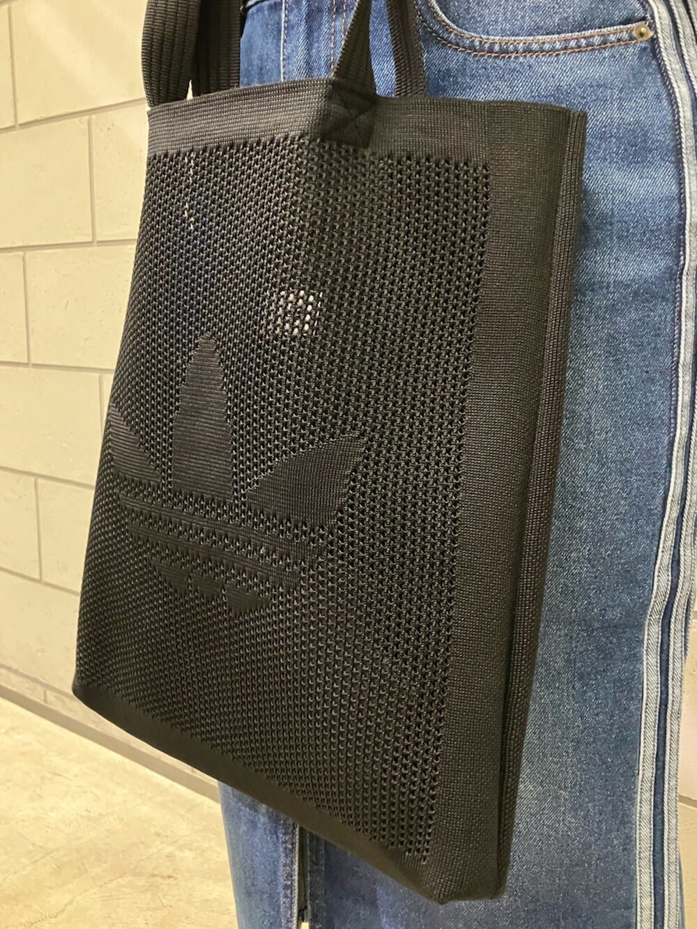 ブラック系のトップス、ブラック系のトートバッグ、ブルー系のデニムスカートを着用したレディースの冬コーディネートの4枚目の写真