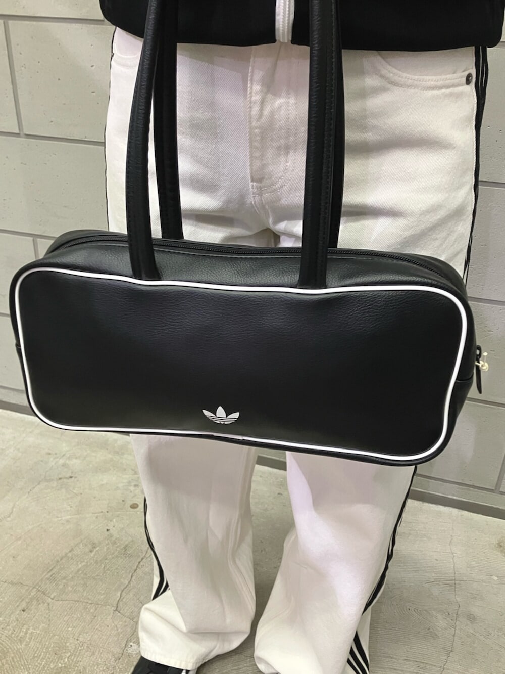 ブラック系のジャージ、ブラック系のシューズ、ブラック系のショルダーバッグを着用したレディースの冬コーディネートの4枚目の写真