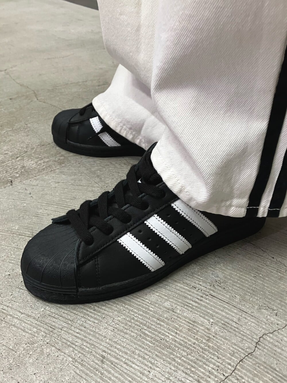 ブラック系のジャージ、ブラック系のシューズ、ブラック系のショルダーバッグを着用したレディースの冬コーディネートの3枚目の写真