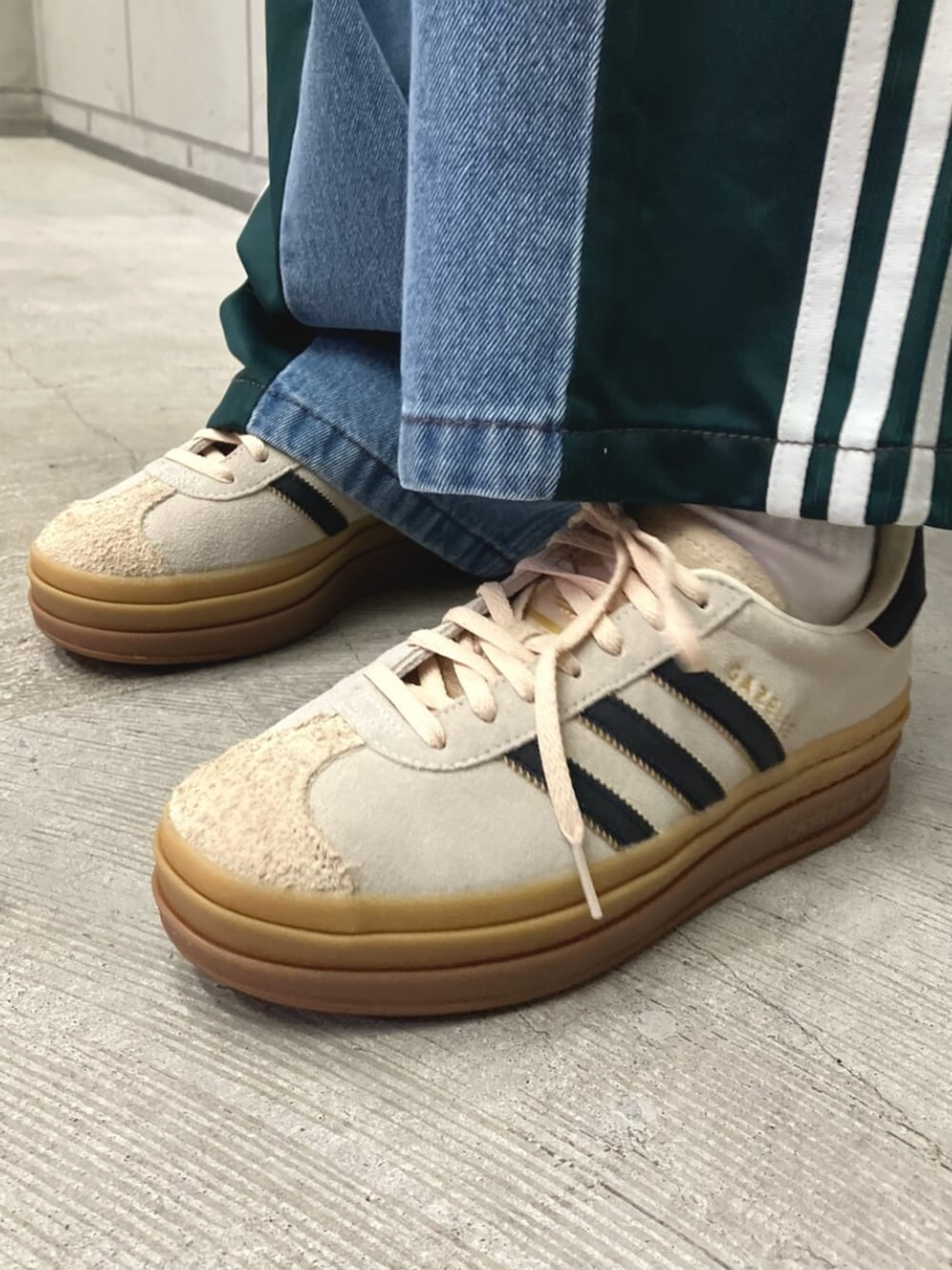 グリーン系のジャージ、ブルー系のデニムパンツ、ホワイト系のスニーカーを着用したレディースの秋コーディネートの4枚目の写真