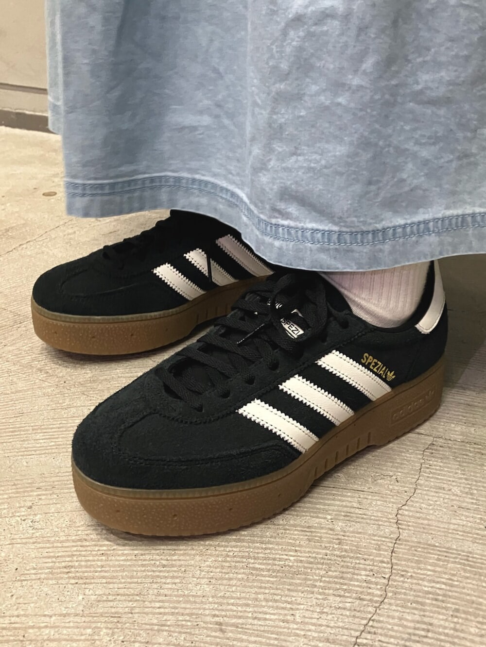 ブルー系のスカート、ブルー系のポロシャツ、ブラック系のスニーカーを着用したレディースの春コーディネートの2枚目の写真