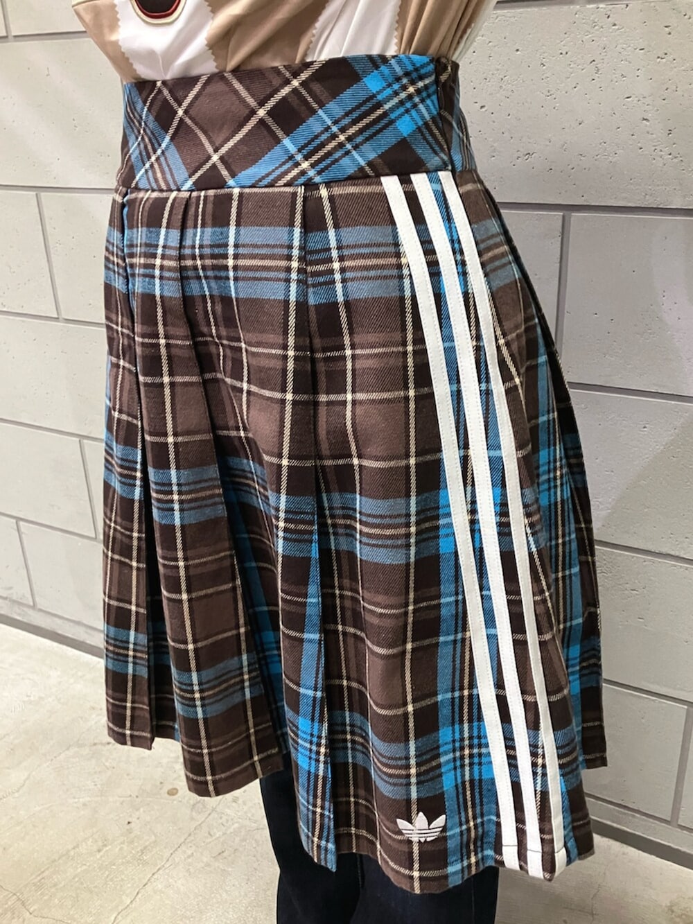 ブラウン系のスカート、ホワイト系のTシャツ/カットソー、ホワイト系のスニーカーを着用したレディースの冬コーディネートの3枚目の写真