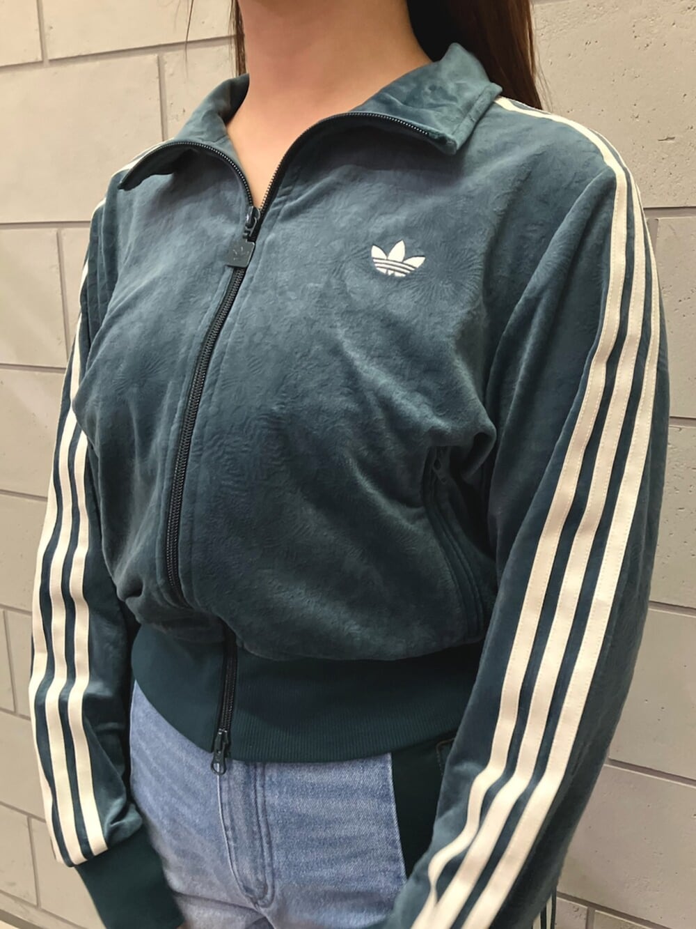 グリーン系のジャージ、ブルー系のデニムパンツ、ホワイト系のスニーカーを着用したレディースの秋コーディネートの2枚目の写真