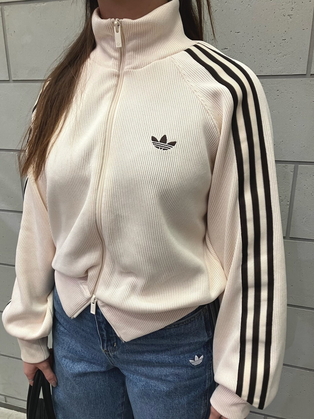 ホワイト系のジャージ、ブルー系のデニムパンツ、ベージュ系のスニーカーを着用したレディースの冬コーディネートの2枚目の写真