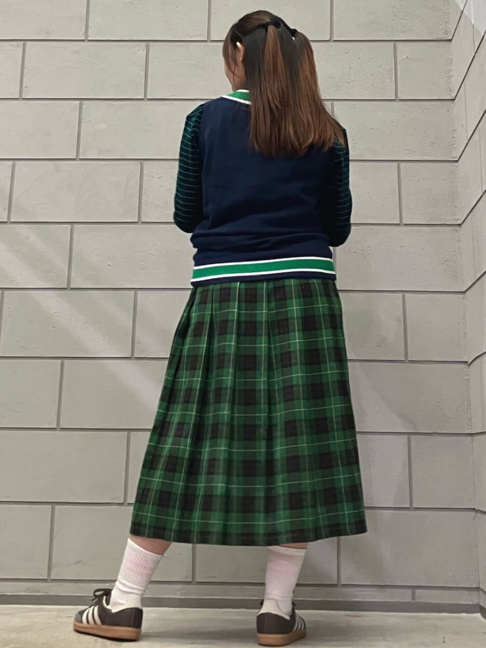 ブルー系のベスト、ブラウン系のスニーカー、ブルー系のポロシャツを着用したレディースの秋コーディネートの2枚目の写真