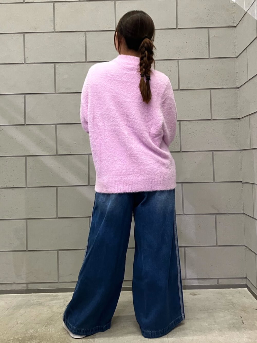 ホワイト系のスニーカー、ブルー系のデニムパンツ、パープル系のニット/セーターを着用したレディースの秋コーディネートの3枚目の写真