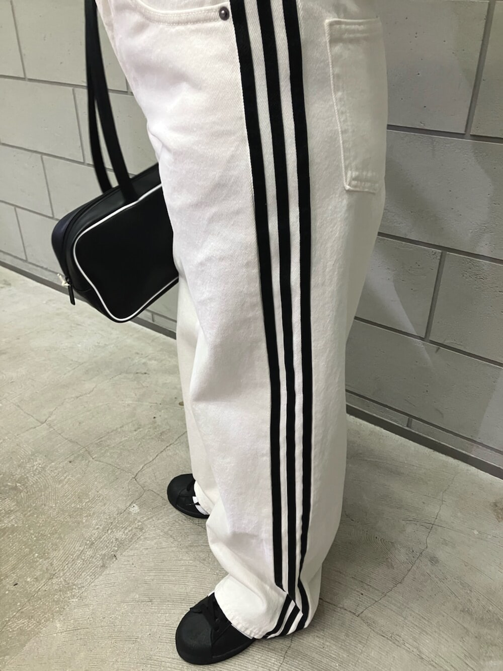 ブラック系のジャージ、ブラック系のシューズ、ブラック系のショルダーバッグを着用したレディースの冬コーディネートの2枚目の写真