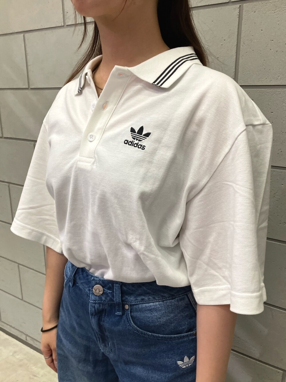 ホワイト系のポロシャツ、ブルー系のデニムパンツ、ブラウン系のスニーカーを着用したレディースの夏コーディネートの4枚目の写真