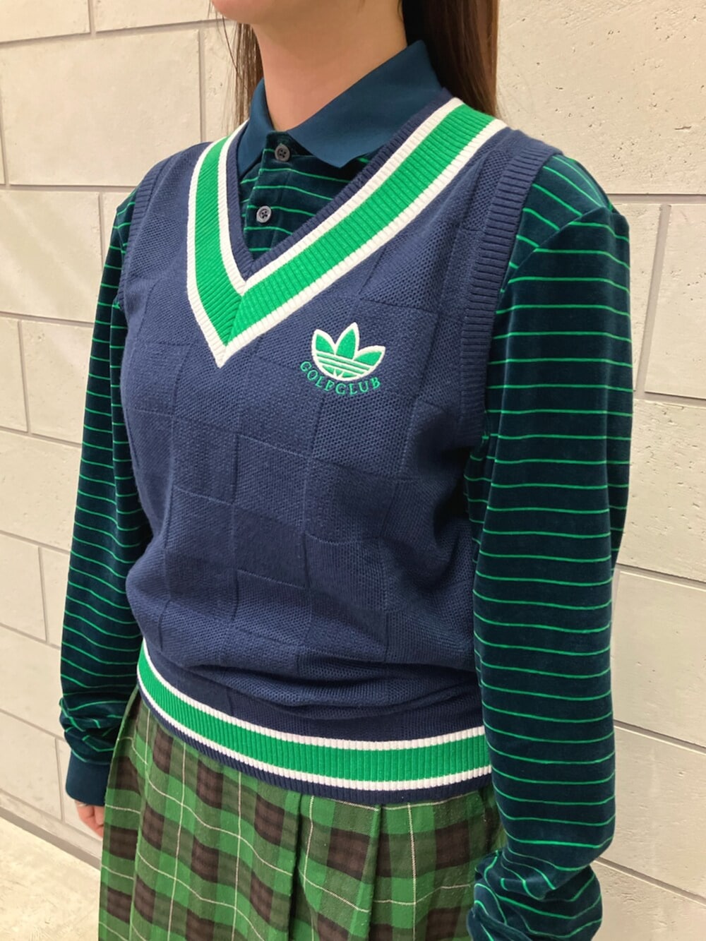 ブルー系のベスト、ブラウン系のスニーカー、ブルー系のポロシャツを着用したレディースの秋コーディネートの3枚目の写真