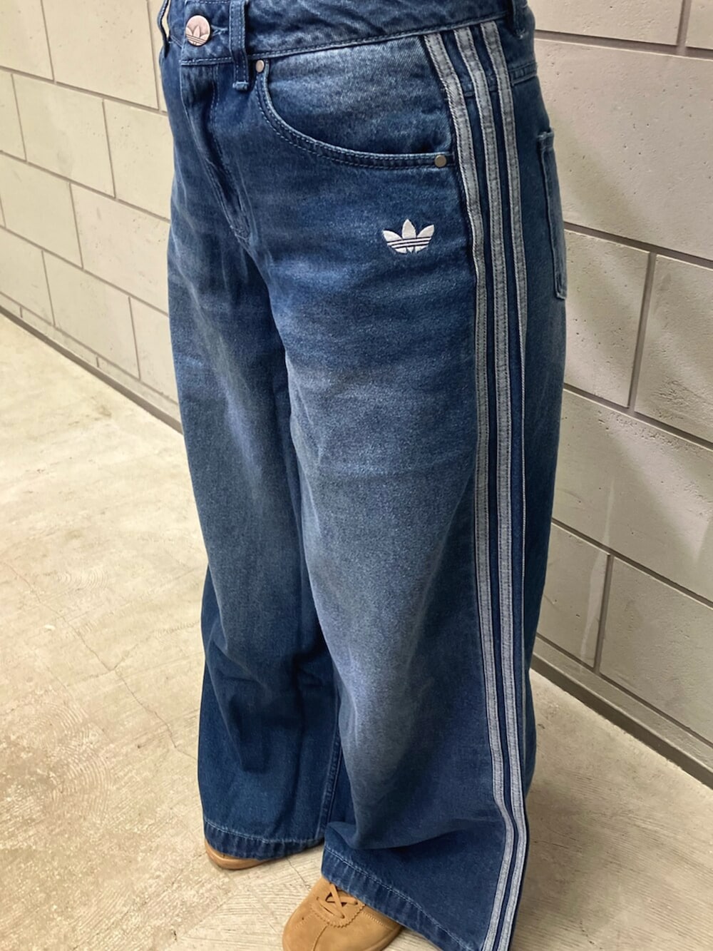 ホワイト系のポロシャツ、ブルー系のデニムパンツ、ブラウン系のスニーカーを着用したレディースの夏コーディネートの5枚目の写真