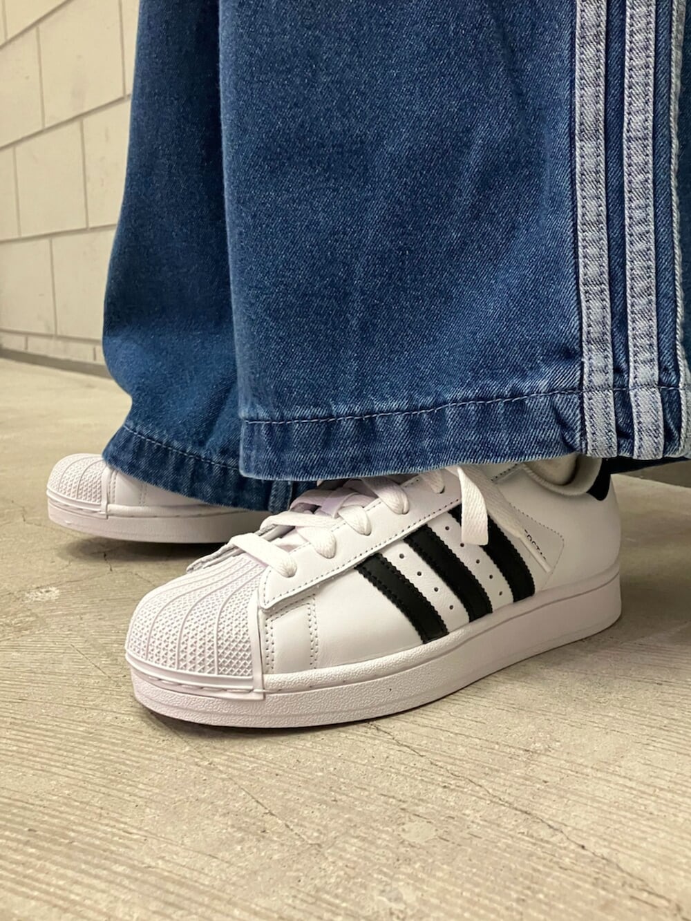 ホワイト系のスニーカー、ブルー系のデニムパンツ、パープル系のニット/セーターを着用したレディースの秋コーディネートの6枚目の写真