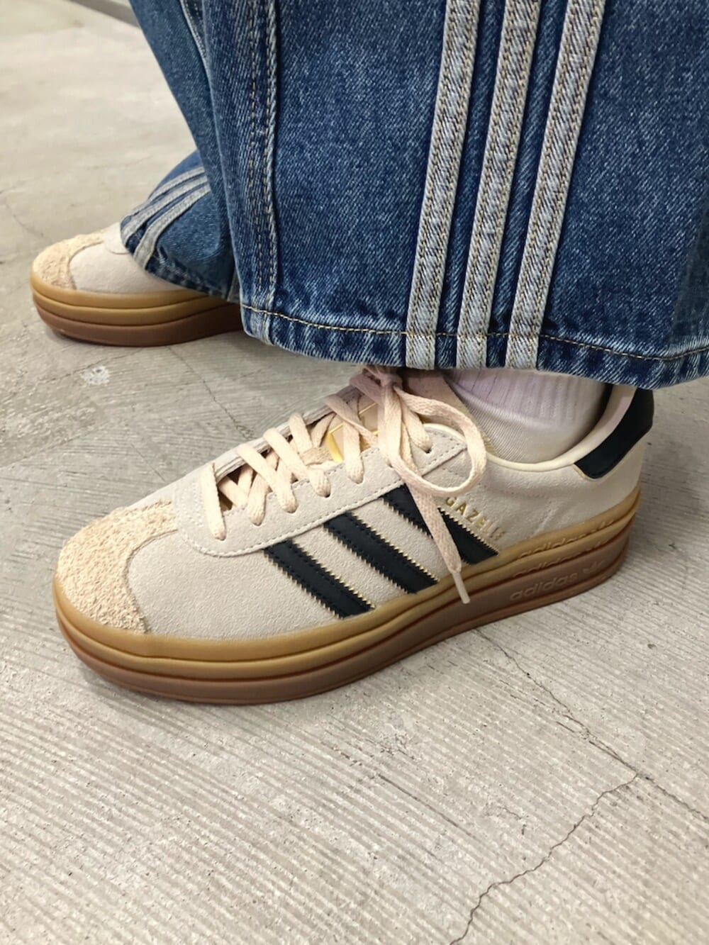 グリーン系のナイロンジャケット、ブルー系のデニムパンツ、ホワイト系のスニーカーを着用したレディースの秋コーディネートの4枚目の写真