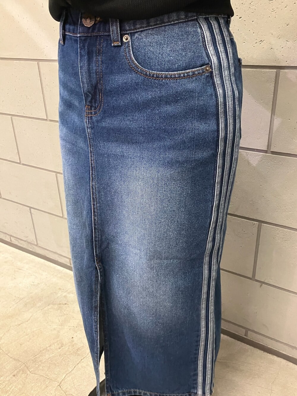 ブラック系のトップス、ブラック系のトートバッグ、ブルー系のデニムスカートを着用したレディースの冬コーディネートの2枚目の写真