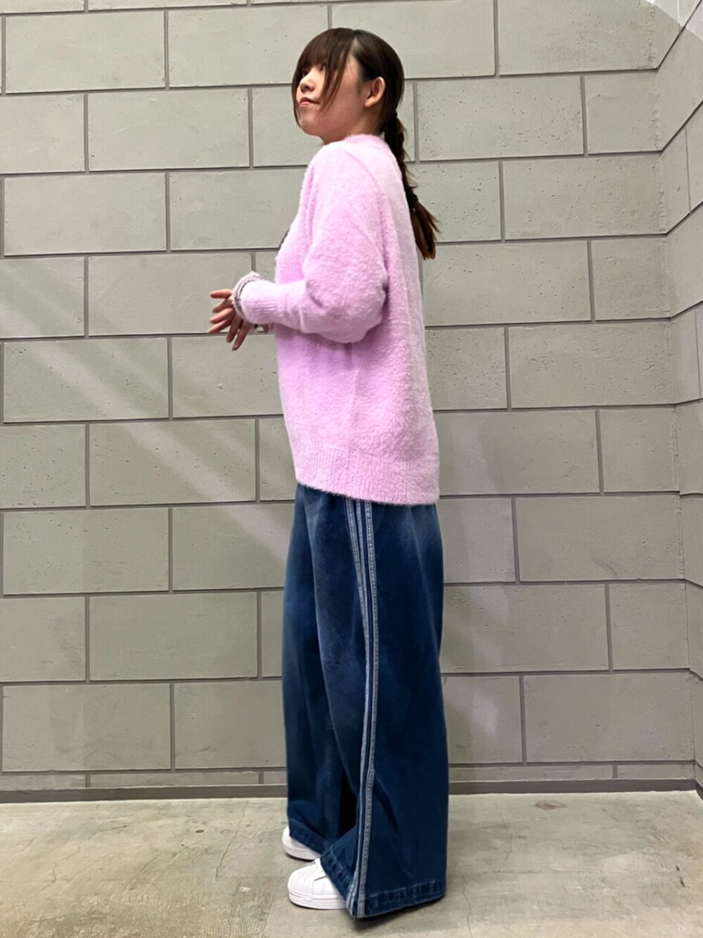 ホワイト系のスニーカー、ブルー系のデニムパンツ、パープル系のニット/セーターを着用したレディースの秋コーディネートの2枚目の写真