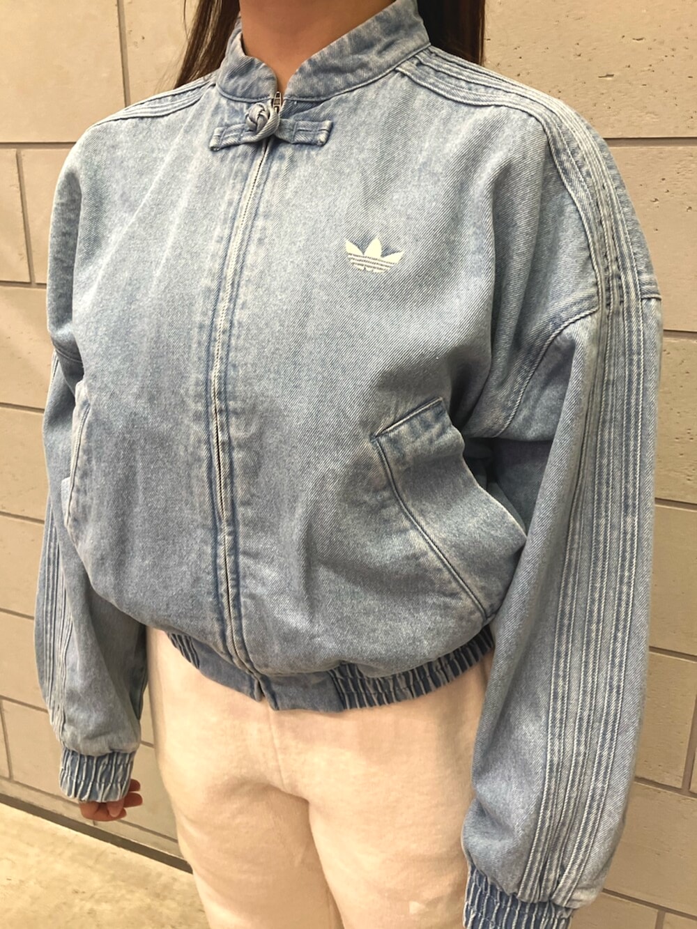 ブルー系のデニムジャケット、ホワイト系のその他パンツ、ブラウン系のスニーカーを着用したレディースの秋コーディネートの2枚目の写真