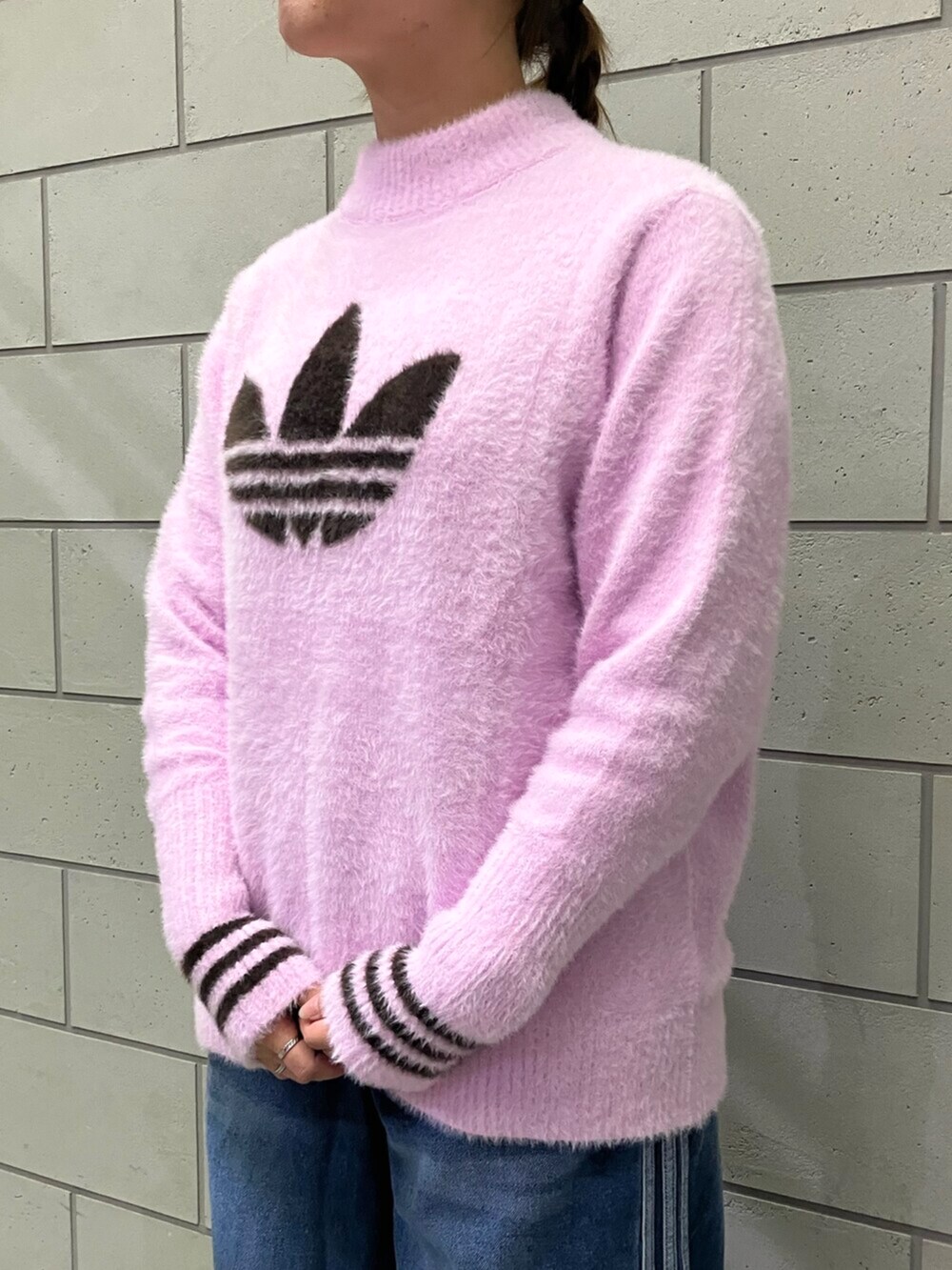 ホワイト系のスニーカー、ブルー系のデニムパンツ、パープル系のニット/セーターを着用したレディースの秋コーディネートの4枚目の写真