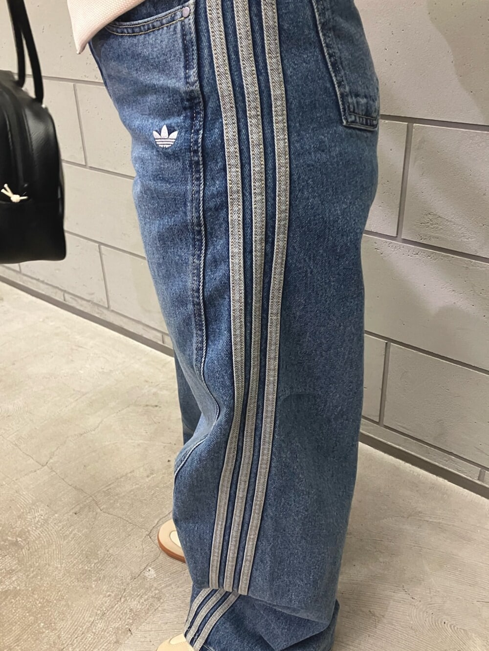 ホワイト系のジャージ、ブルー系のデニムパンツ、ベージュ系のスニーカーを着用したレディースの冬コーディネートの3枚目の写真