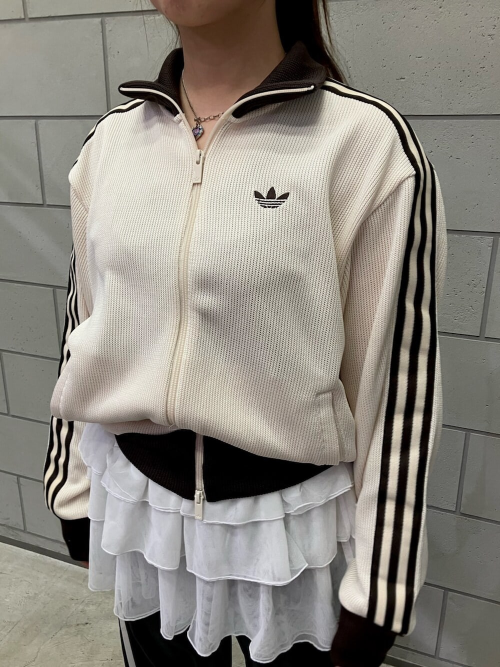 ホワイト系のジャージ、ブラック系のスウェットパンツ、ブラック系のシューズを着用したレディースの冬コーディネートの2枚目の写真