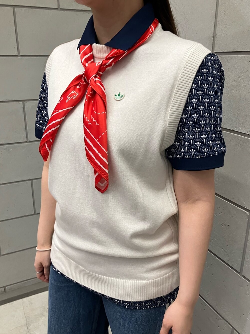 ブルー系のポロシャツ、ホワイト系のベスト、ブラウン系のスニーカーを着用したレディースの春コーディネートの2枚目の写真