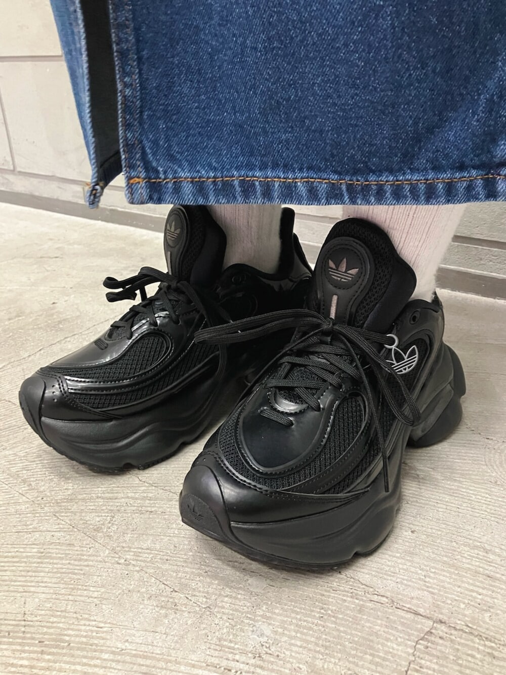 ブラック系のトップス、ブラック系のトートバッグ、ブルー系のデニムスカートを着用したレディースの冬コーディネートの3枚目の写真