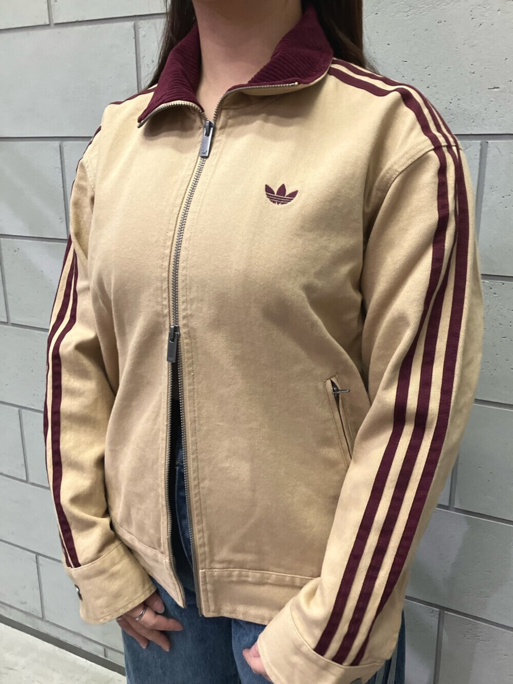 グリーン系のナイロンジャケット、ブルー系のデニムパンツ、ホワイト系のスニーカーを着用したレディースの秋コーディネートの2枚目の写真