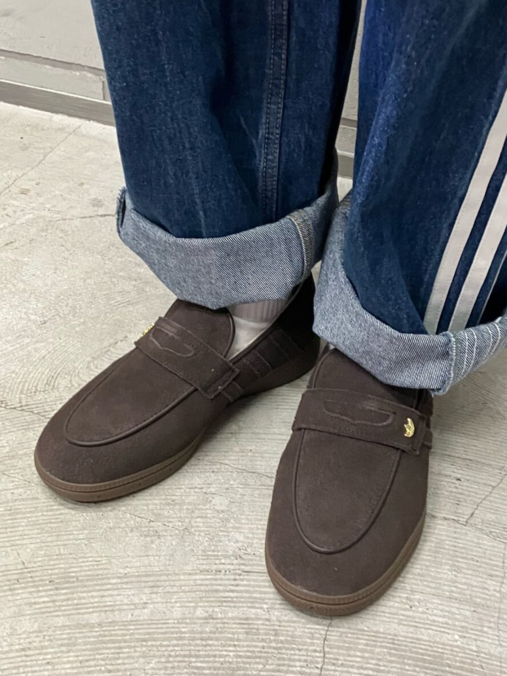 ブラウン系のスカート、ブルー系のベスト、ブラウン系のスニーカーを着用したレディースの春コーディネートの2枚目の写真