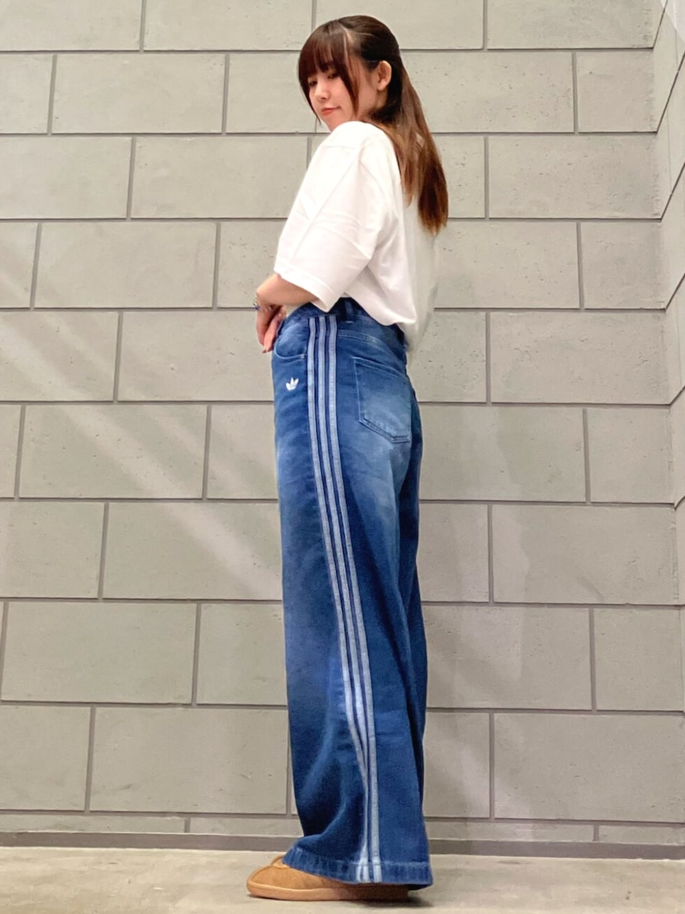 ホワイト系のポロシャツ、ブルー系のデニムパンツ、ブラウン系のスニーカーを着用したレディースの夏コーディネートの2枚目の写真