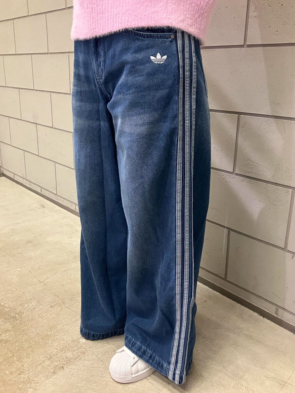 ホワイト系のスニーカー、ブルー系のデニムパンツ、パープル系のニット/セーターを着用したレディースの秋コーディネートの5枚目の写真