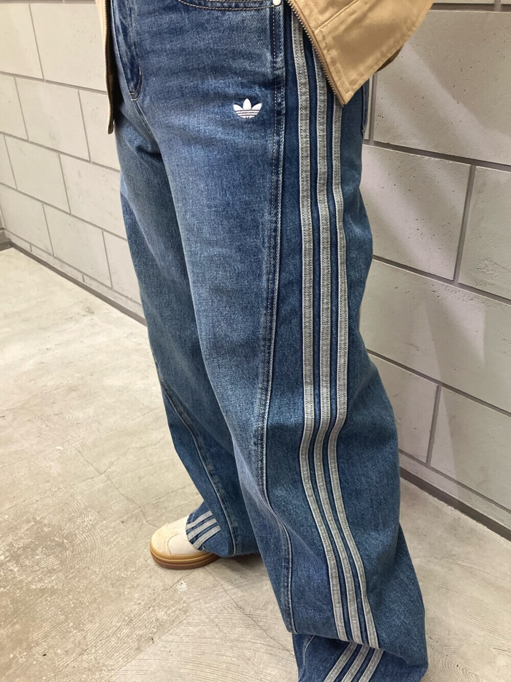 グリーン系のナイロンジャケット、ブルー系のデニムパンツ、ホワイト系のスニーカーを着用したレディースの秋コーディネートの3枚目の写真