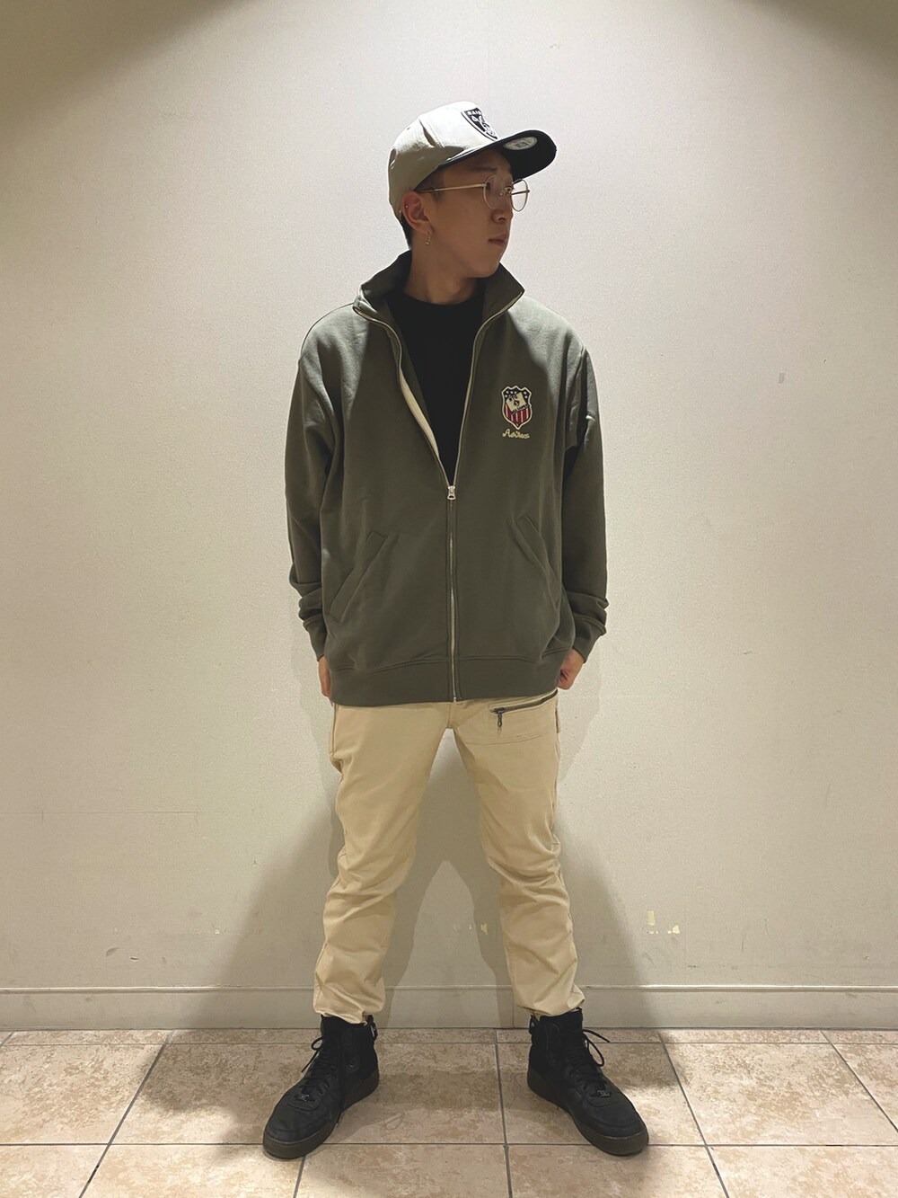 ベージュ系のパンツ、グリーン系のジャージ、ブラック系のTシャツ/カットソーを着用したメンズの春コーディネートの2枚目の写真