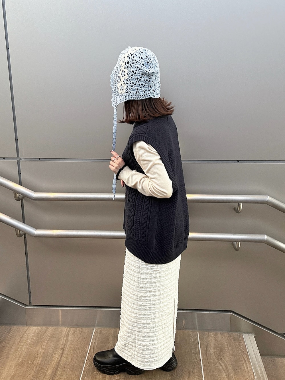 ブルー系のベスト、ブラック系のブーツ、ブルー系のハットを着用したレディースの春コーディネートの2枚目の写真