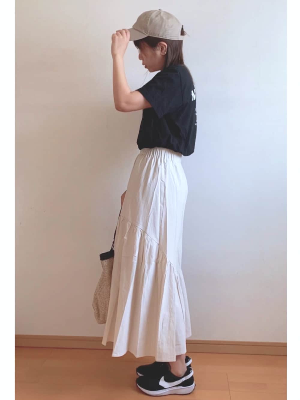 ブラック系のTシャツ/カットソー、ベージュ系のかごバッグ、ホワイト系のスカートを着用したレディースの夏コーディネートの2枚目の写真