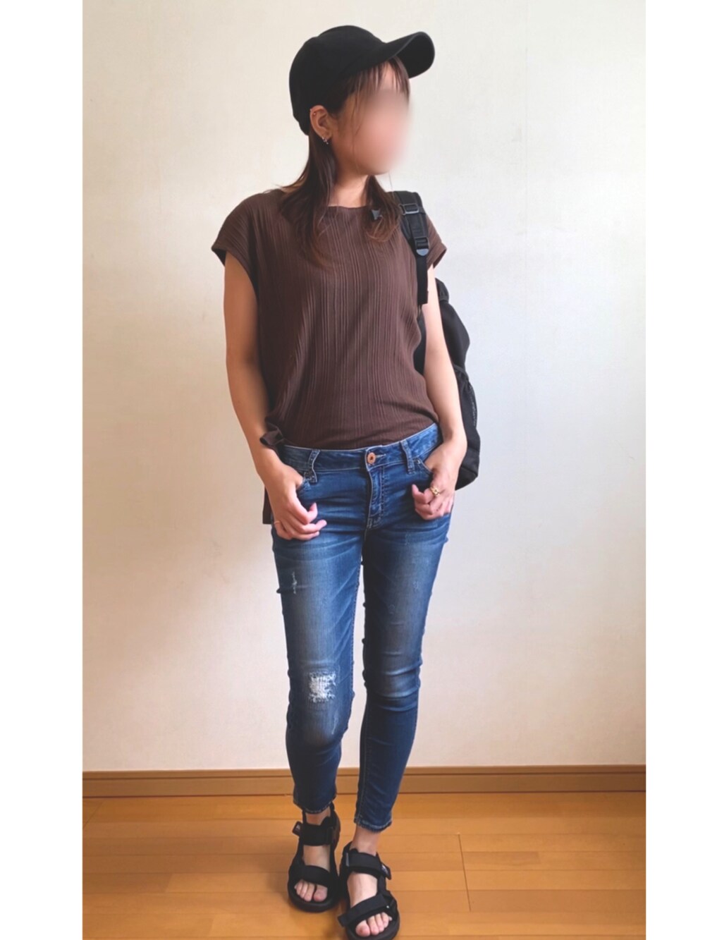 ブラック系のバックパック/リュック、ブラウン系のTシャツ/カットソー、ブルー系のデニムパンツを着用したレディースの夏コーディネートの2枚目の写真