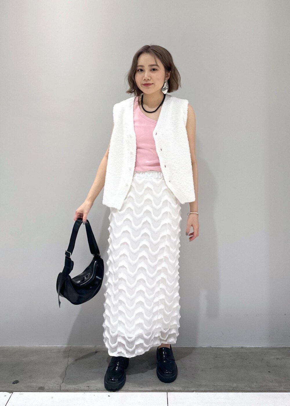 ブラック系のローファー、ブラック系のショルダーバッグ、ホワイト系のベストを着用したレディースの春コーディネートの8枚目の写真