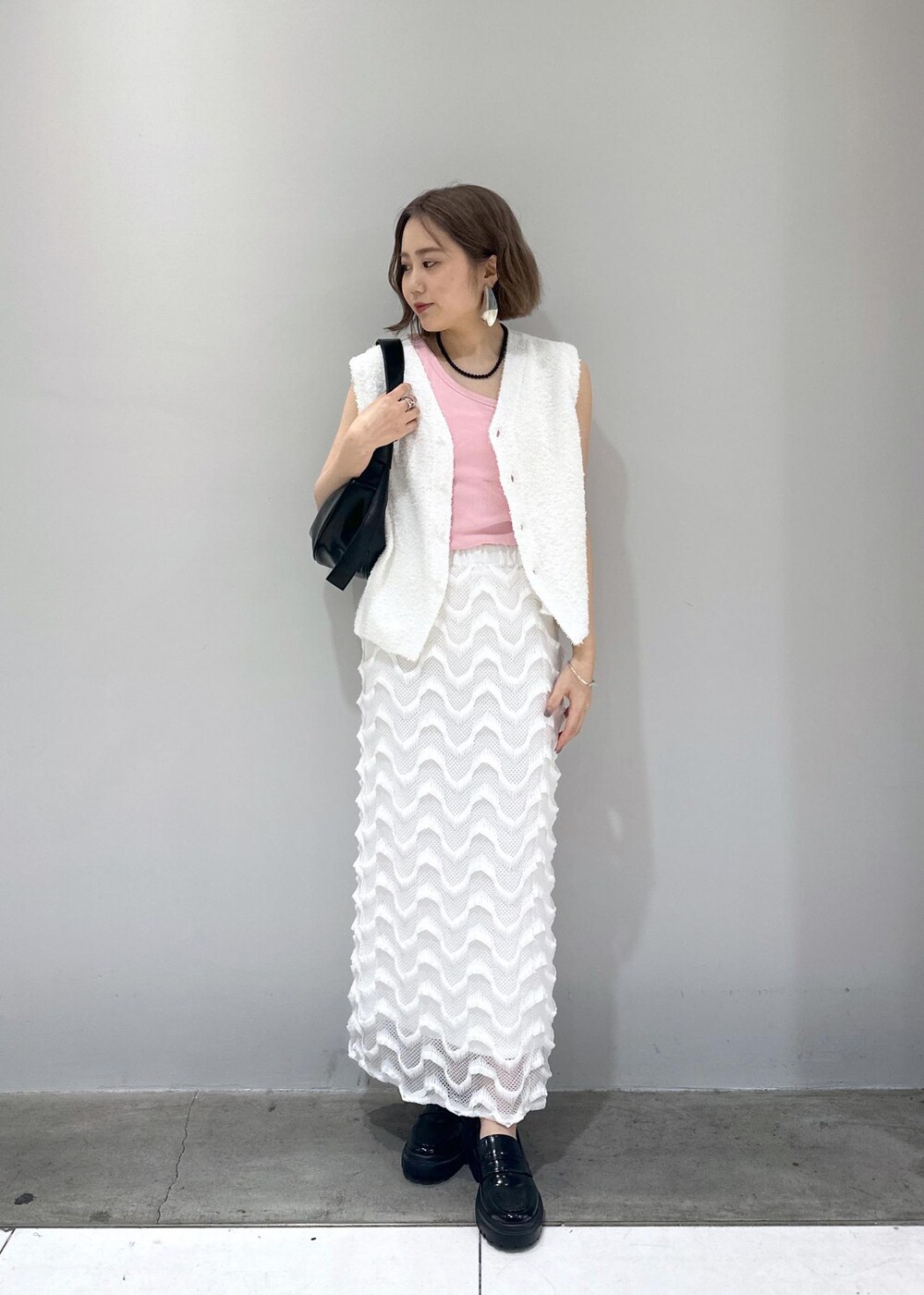 ブラック系のローファー、ブラック系のショルダーバッグ、ホワイト系のベストを着用したレディースの春コーディネートの7枚目の写真