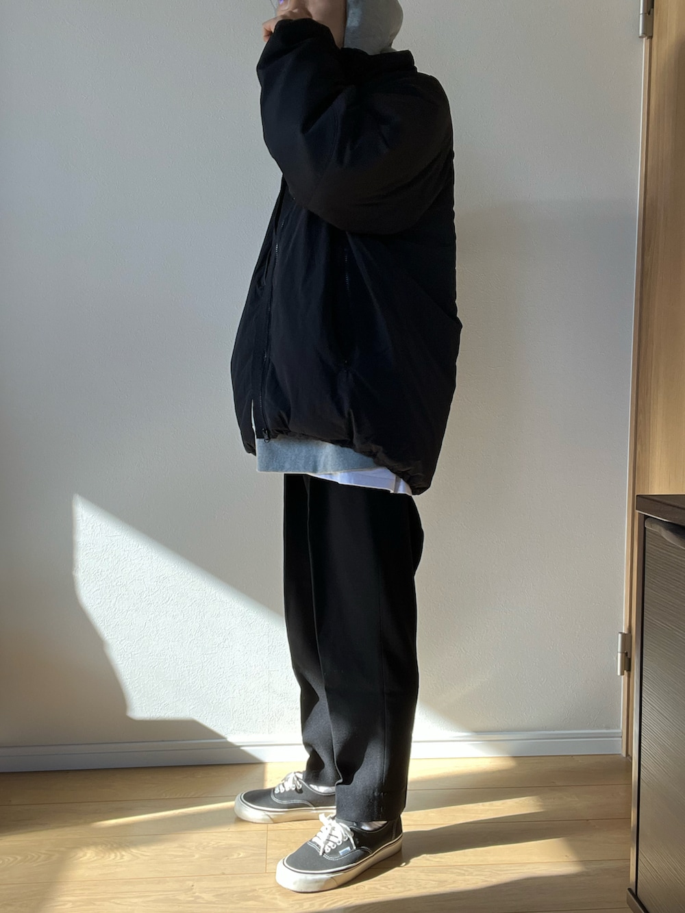 ブラック系のブルゾン、グレー系のパーカー、ブラック系のスラックスを着用したメンズの冬コーディネートの2枚目の写真