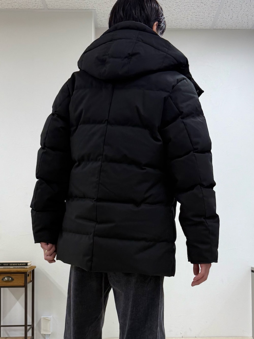 ブラック系のダウンジャケット/コート、ベージュ系のニット/セーター、グレー系のその他パンツを着用したメンズの秋コーディネートの3枚目の写真